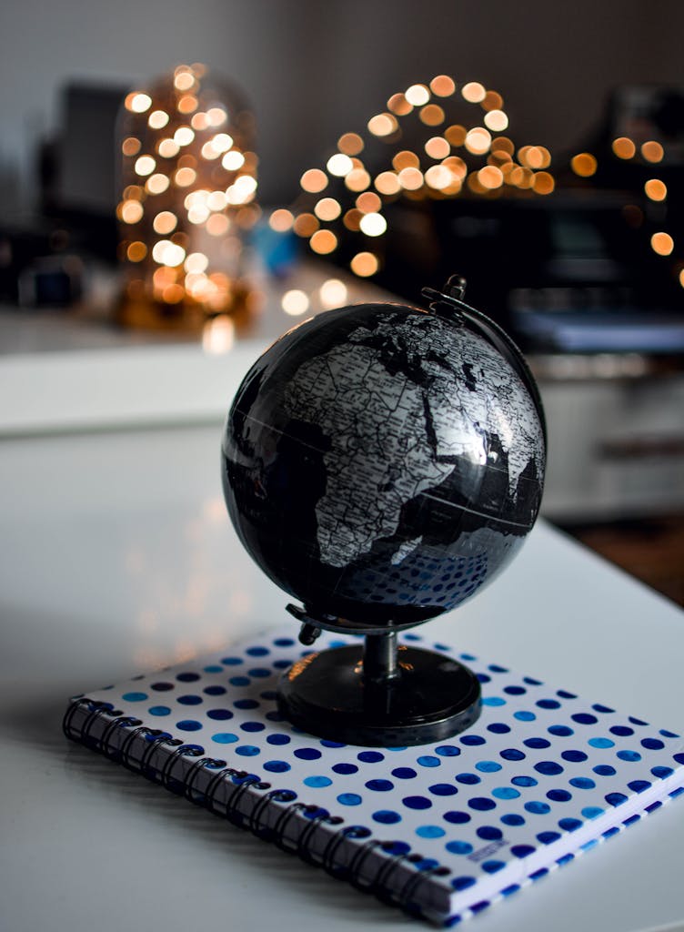 Career Counseling Services for Pakistani Students 3 Elegant black globe and notebook against warm bokeh lights, perfect for educational themes.